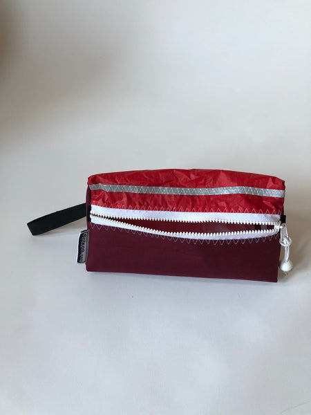 Trianglar shaped storage case for toiletries, and essentials for travel. Sits solidly on surface. Wrist strap made of webbing and heavy duty zip. Lined.
