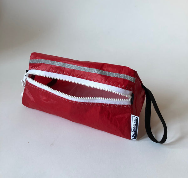 Trianglar shaped storage case for toiletries, and essentials for travel. Sits solidly on surface. Wrist strap made of webbing and heavy duty zip. Lined.